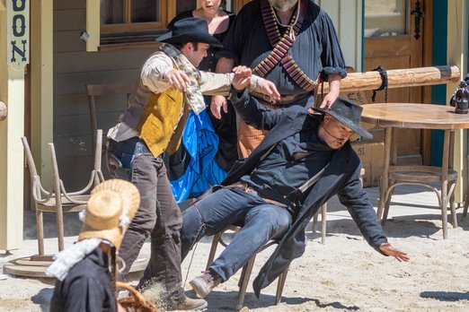 Cowboy stoßt Mann von Stuhl