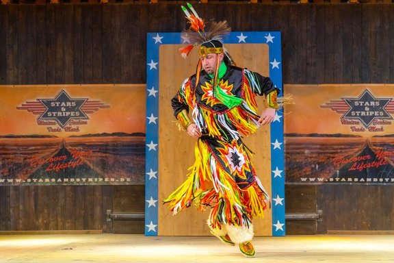Mann in Klamotten mit bunten Fransen führt spektakulärer indianischer Tanz auf