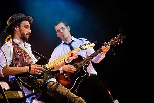 zwei Männer mit Gitarre und E-Gitarre auf einer Bühne