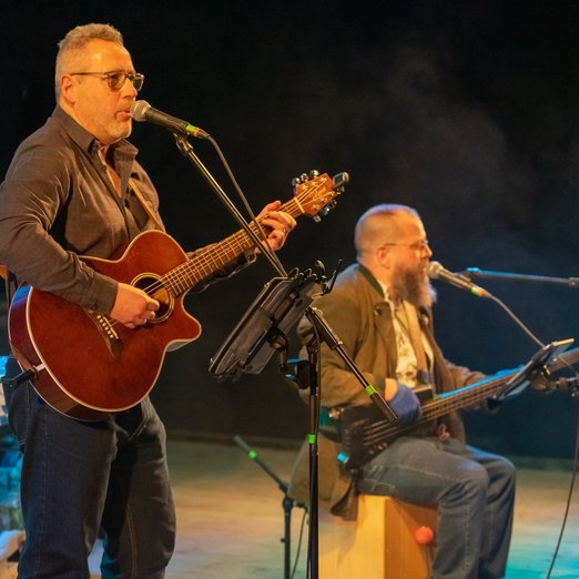Zwei Männer auf einer Bühne spielen Gitarre und singen