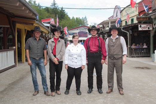 Vier Männer mit Cowboyhüten und eine Köchin