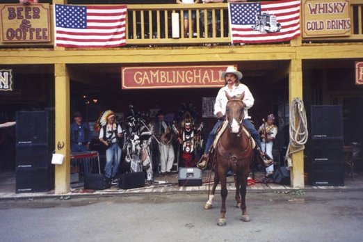 Mann in Cowboykleidung sitzt auf Pferd