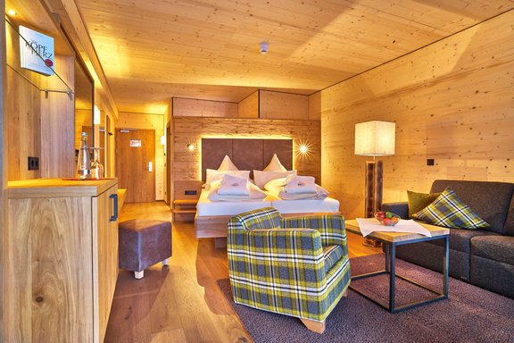 Hotelzimmer mit Holzwänden, Doppelbett und Sofa