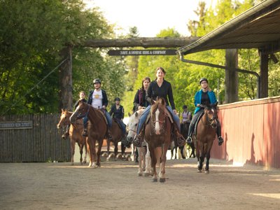 Menschen reiten mit ihren Pferden durch ein Tor
