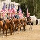Menschen auf Pferden halten Flagge der USA