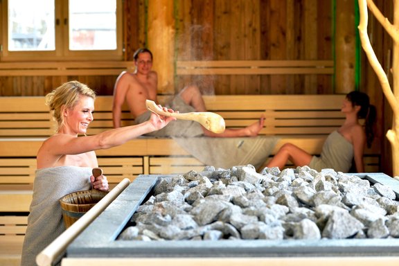 Frau macht einen Aufguss in einer Sauna