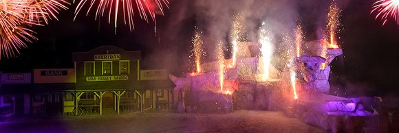 Ein spektakuläres Feuerwerk erleuchtet den Nachthimmel über einer belebten Veranstaltung, während Menschen gebannt zuschauen.