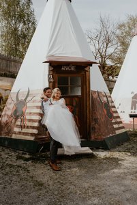 Bräutigam trägt Braut vor einem Tipi