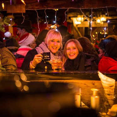 Zwei Frauen trinken an einem Stand Glühwein