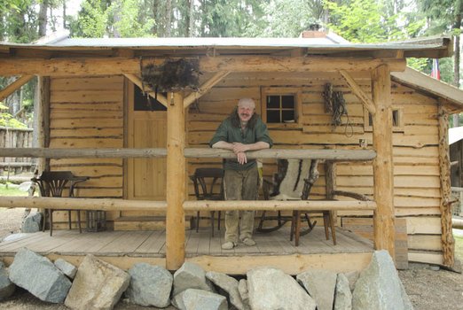 Mann steht auf der Veranda einer Holzhütte