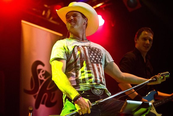 Mann mit Cowboyhut und Mikrofon auf einer Bühne