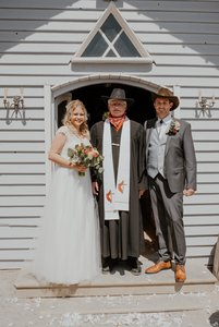Brautpaar mit Priester vor der Kirche