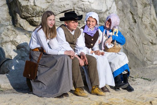 Kinder in authentischer Kleidung sitzen auf einem Stein