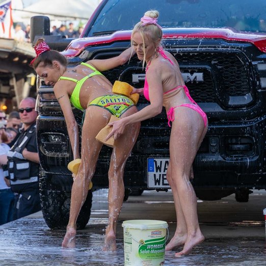 Zwei Frauen in Bikini waschen ein Auto