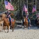 Frauen reiten auf Pferden und halten die amerikanische Flagge