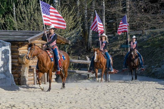 Frauen reiten auf Pferden und halten die amerikanische Flagge