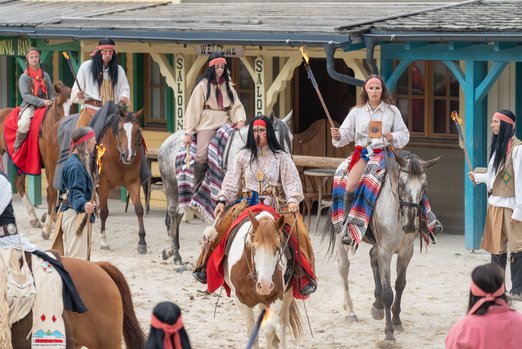 Indianer reiten auf Pferden durch die Westernstadt