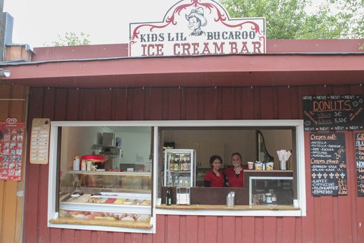 Zwei Frauen stehen in einem Verkaufsstand für Eis, Crêpes und Donuts
