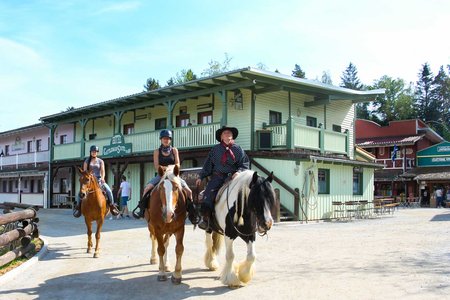 Drei Personen reiten auf ihren Pferden durch die Stadt