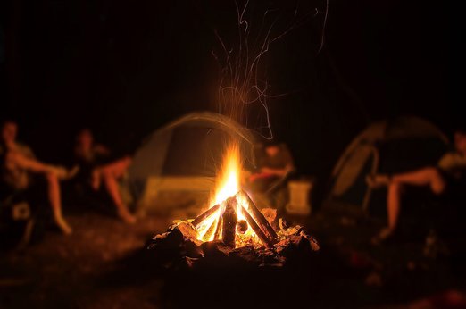Lagerfeuer mit Zelte und Menschen im Hintergrund