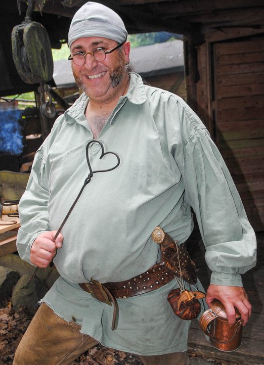 Mann in authentischer Kleidung mit Metallstab in Herzform