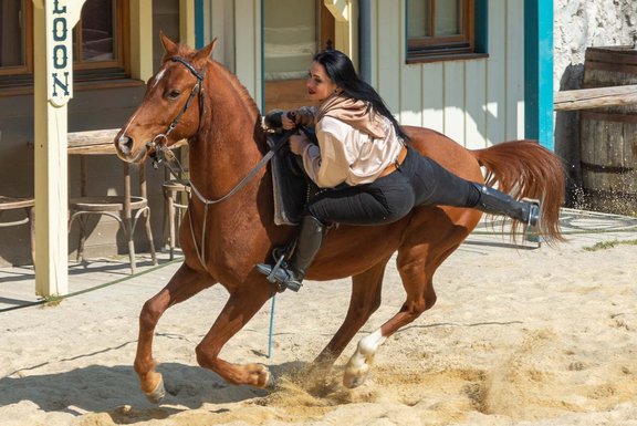 Eine Frau schwingt sich auf ein laufendes Pferd