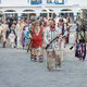 Menschen in indianischer Kleidung gehen durch eine Stadt
