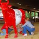 Zwei Personen melken eine künstliche rote Kuh