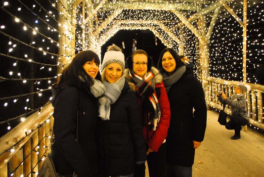 Vier Frauen stehen auf einer Brücke, die mit einer großen Lichterkette geschmückt ist