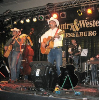 Fünf Musiker mit Cowboyhüten auf einer Bühne