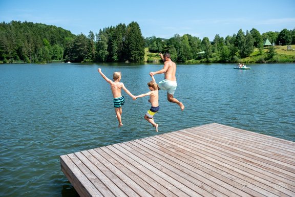 Zwei Kinder und ein Mann springen in Wasser