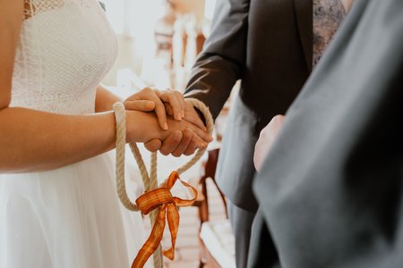 Braut und Bräutigam halten ihre Hände mit Seil verbunden