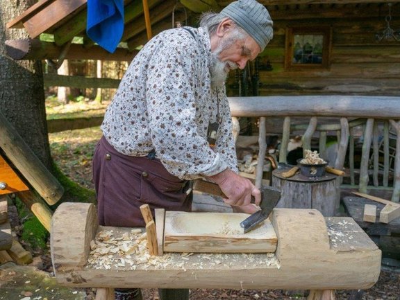 Mann schnitzt eine Schale aus einem Holzblock