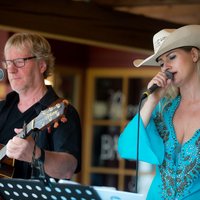 Frau singt in ein Mikrofon, Mann spielt Gitarre