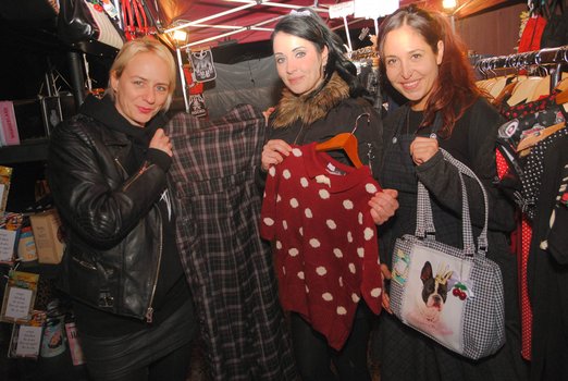 Drei Frauen halten ein Kleid, einen Pullover und eine Tasche