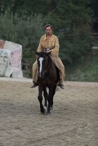 Mann in Indianerkleidung reitet auf einem Pferd