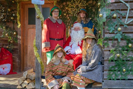 Fünf Menschen verkleidet als Weihnachtsmann und Elfen